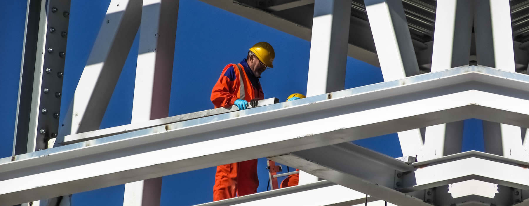trabajador con su equipo de seguridad laborando en una estructura metalica en un trabajo de riesgo asegurado por seguro sctr